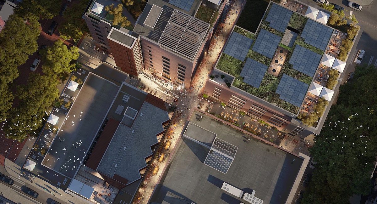 Aerial rendering of Populus Seattle’s buildings and alleyway at dusk, showcasing rooftop gardens, solar panels, outdoor dining areas with umbrellas, and a lively pedestrian plaza surrounded by greenery.