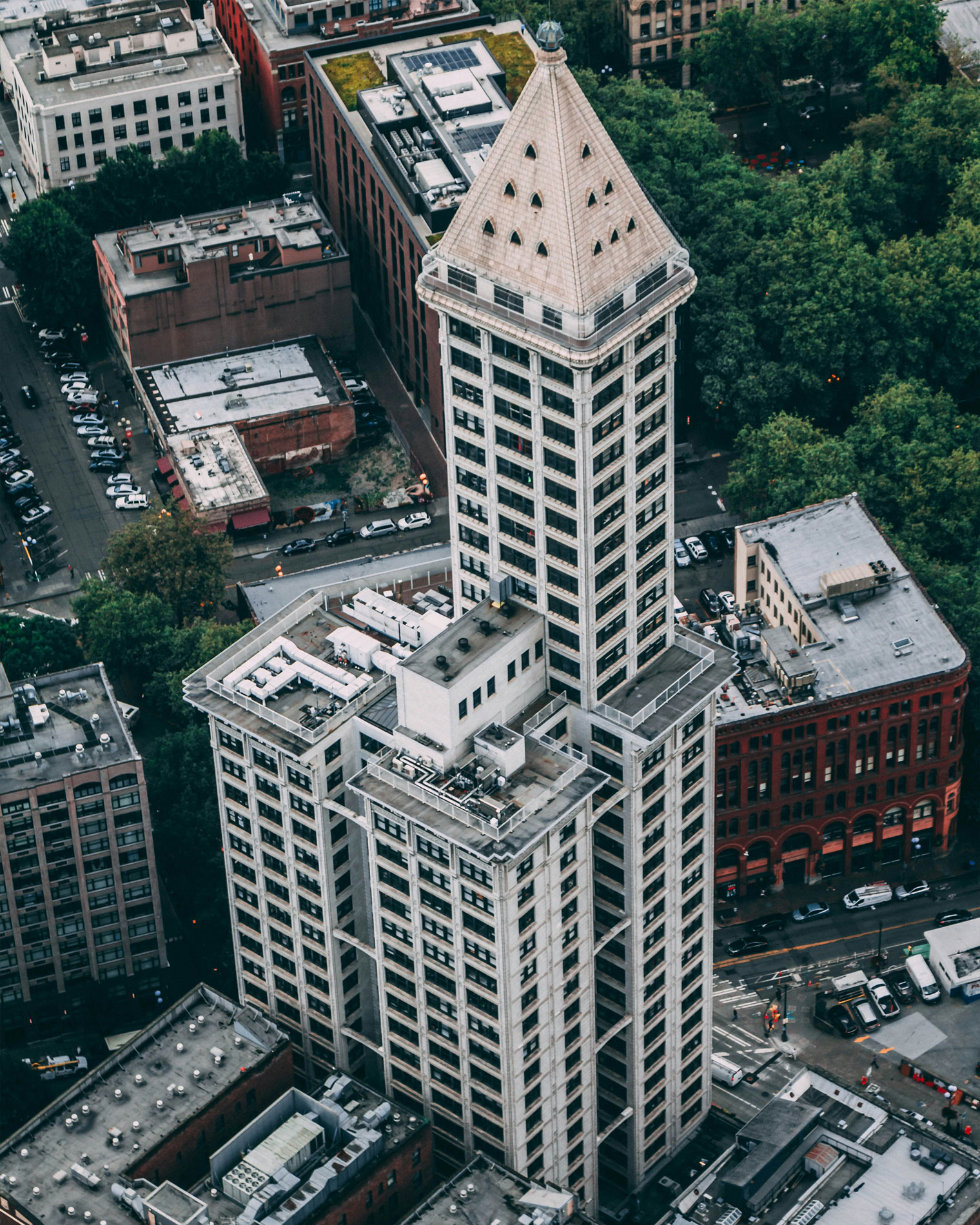 Aerial view of Smith Tower in Seattle’s Pioneer Square, showcasing its pyramid-shaped roof, historic architecture, and surrounding city blocks with a mix of brick buildings and tree-lined streets.