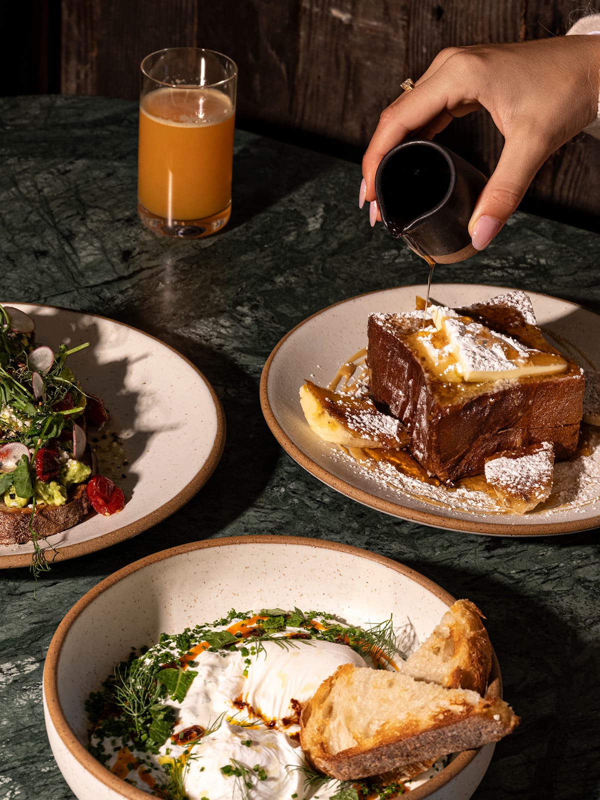Three plated dishes at Salt Harvest featuring different popular breakfast options like French Toast, Turkish eggs, and avocado toast.